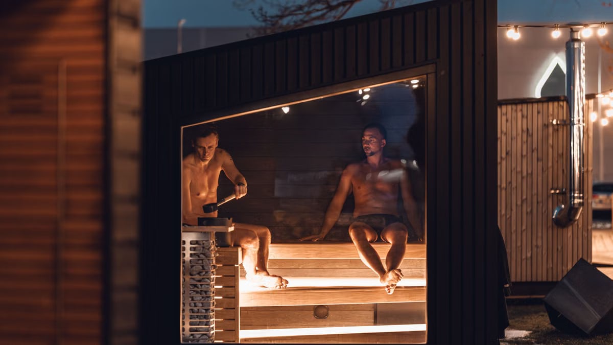 Two men relax in a modern Nordic sauna cabin, enjoying a tranquil evening.